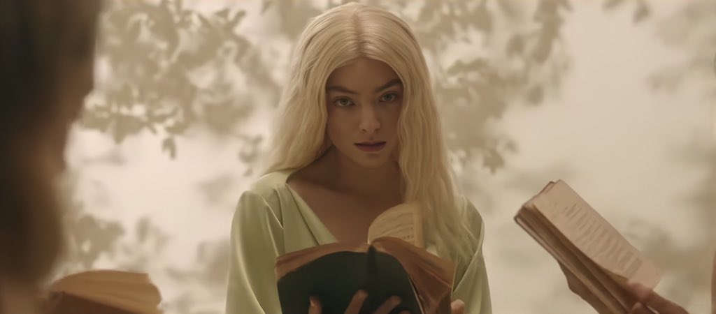 Lorde holding a book open in her new music video.